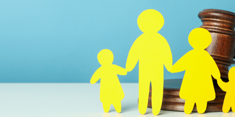 Yellow paper cut into the shape of a family of two adults and two children all holding hands