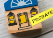 A toy wooden house with a yellow arrow sticker that says probate