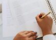 A person signing a document with a pen