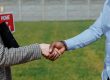 Two outstretched arms shaking hands