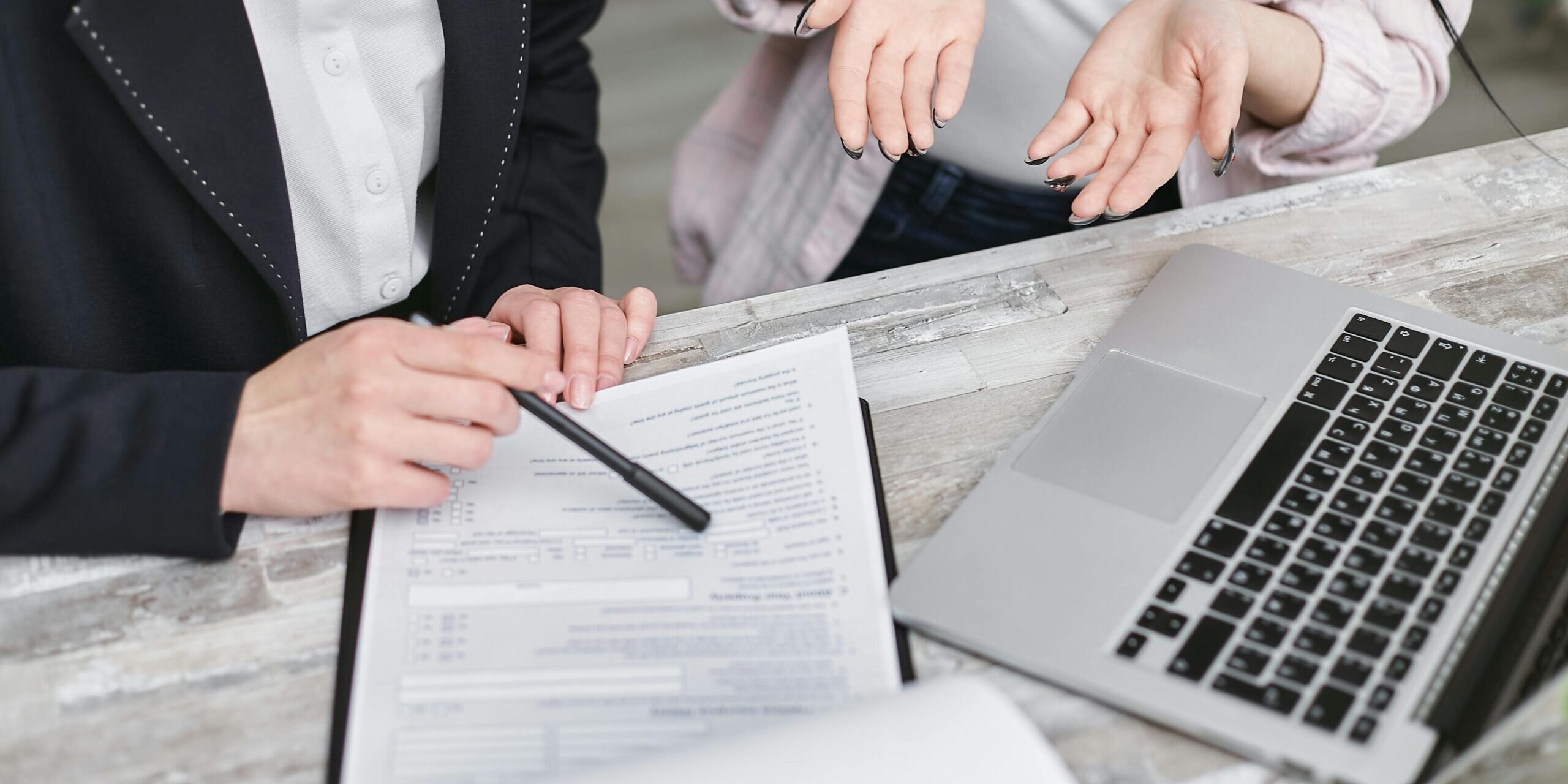 Legal document Two people sat at a table in front of a form and a laptop